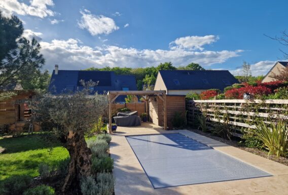Piscine contemporaine avec escalier immergé, pergola couverte et aménagement paysager - Réalisation pisciniste Angers