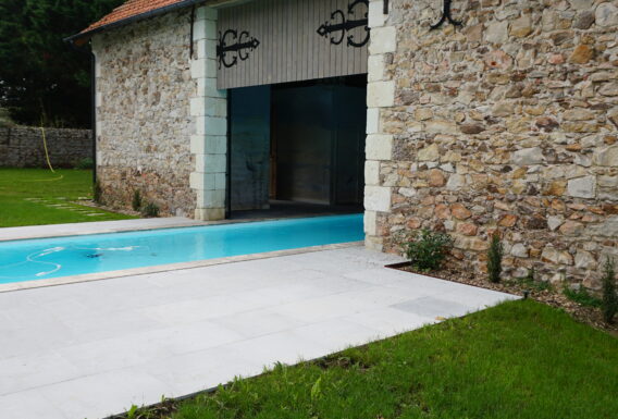 Piscine rectangulaire avec margelles en pierre naturelle et escalier immergé - Réalisation pisciniste Angers