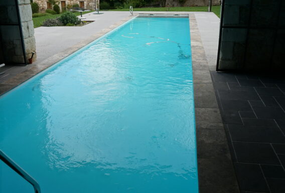 Piscine rectangulaire avec margelles en pierre naturelle et escalier immergé - Réalisation pisciniste Angers