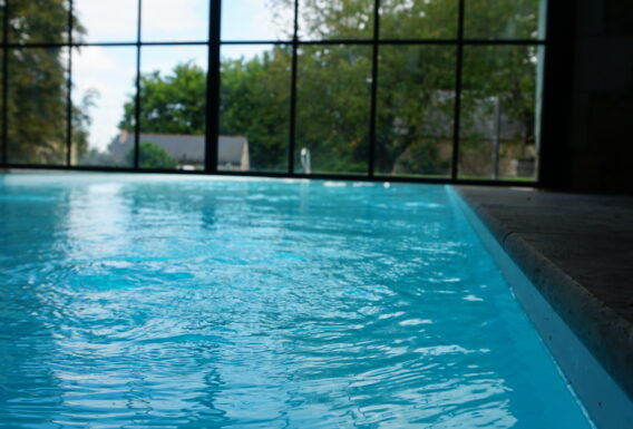 Piscine intérieure-extérieure avec grande baie vitrée ouvrant sur jardin - Installation pisciniste Angers
