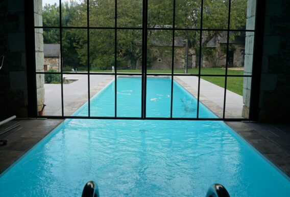 Bassin de nage intérieur avec verrière offrant vue panoramique sur jardin - Installation pisciniste Angers