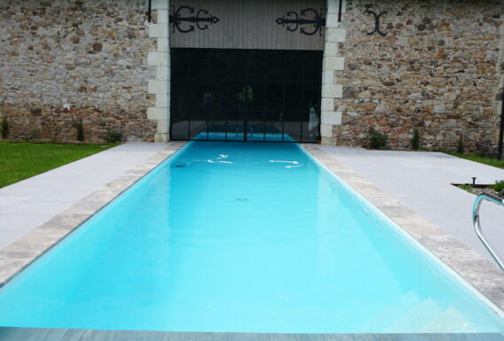 Piscine à débordement avec margelles en pierre et bâtiment rénové - Construction pisciniste Angers