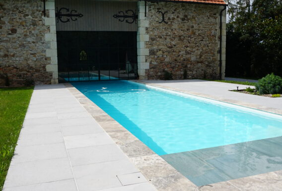 Piscine extérieure avec escalier immergé en pierre et bâtiment rénové - Construction pisciniste Angers